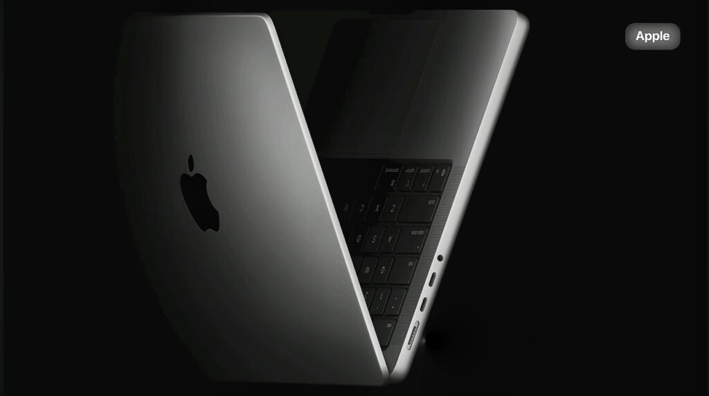 Partially open Apple MacBook Showing Slim aluminium design, keyboard and side ports against a dark background.